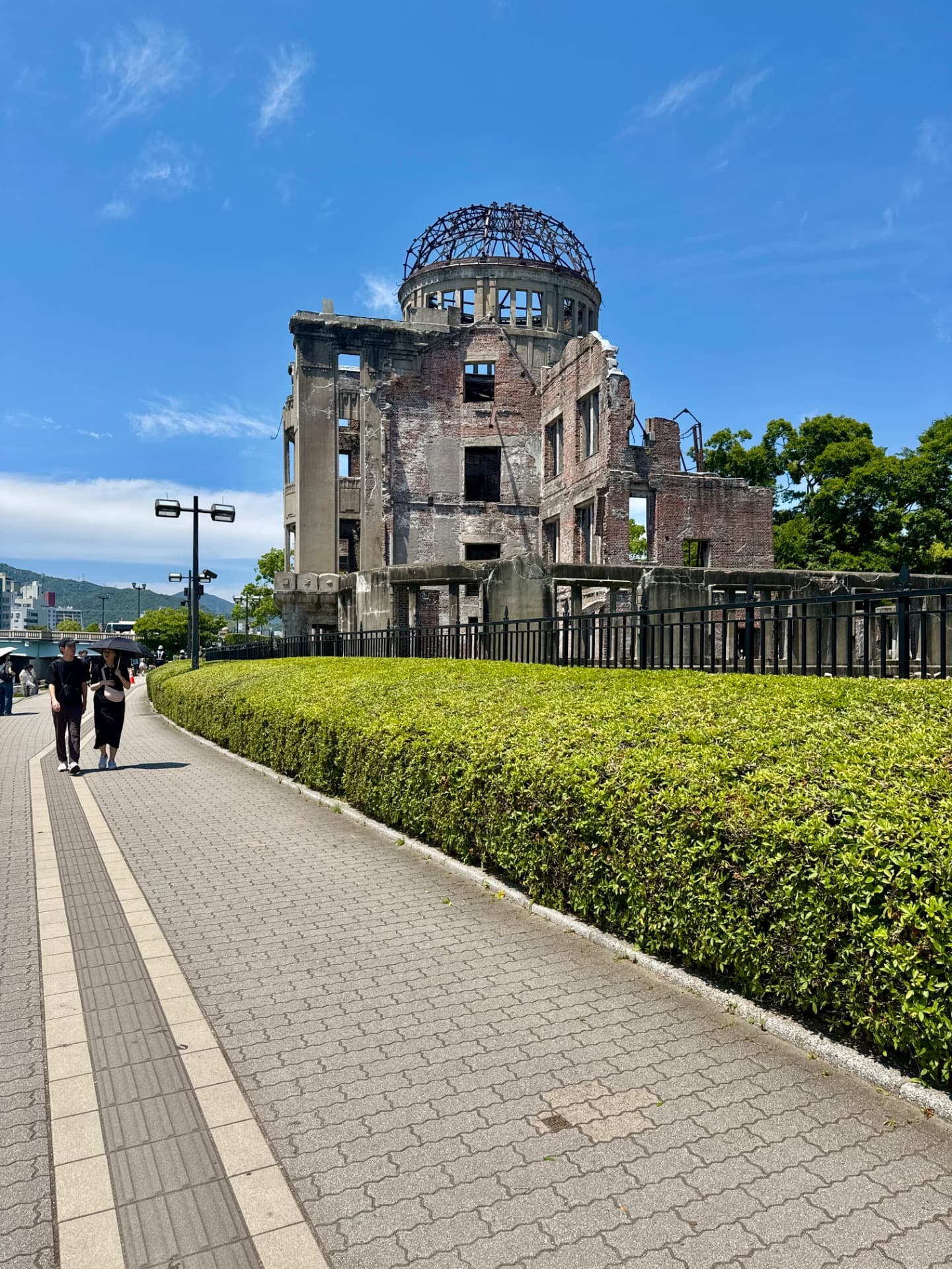 Hiroshima Peace Memorial Dome, a historic ruined structure with distinctive domed framework surrounded by manicured hedges and walking path.