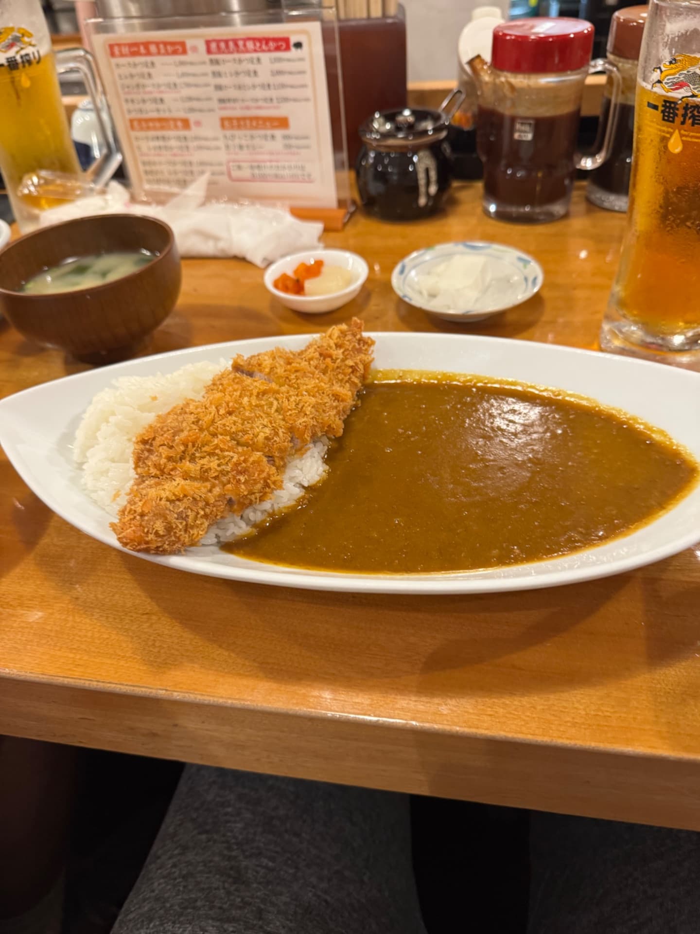 Breaded cutlet with rice and curry sauce served on a white plate at a Japanese restaurant.
