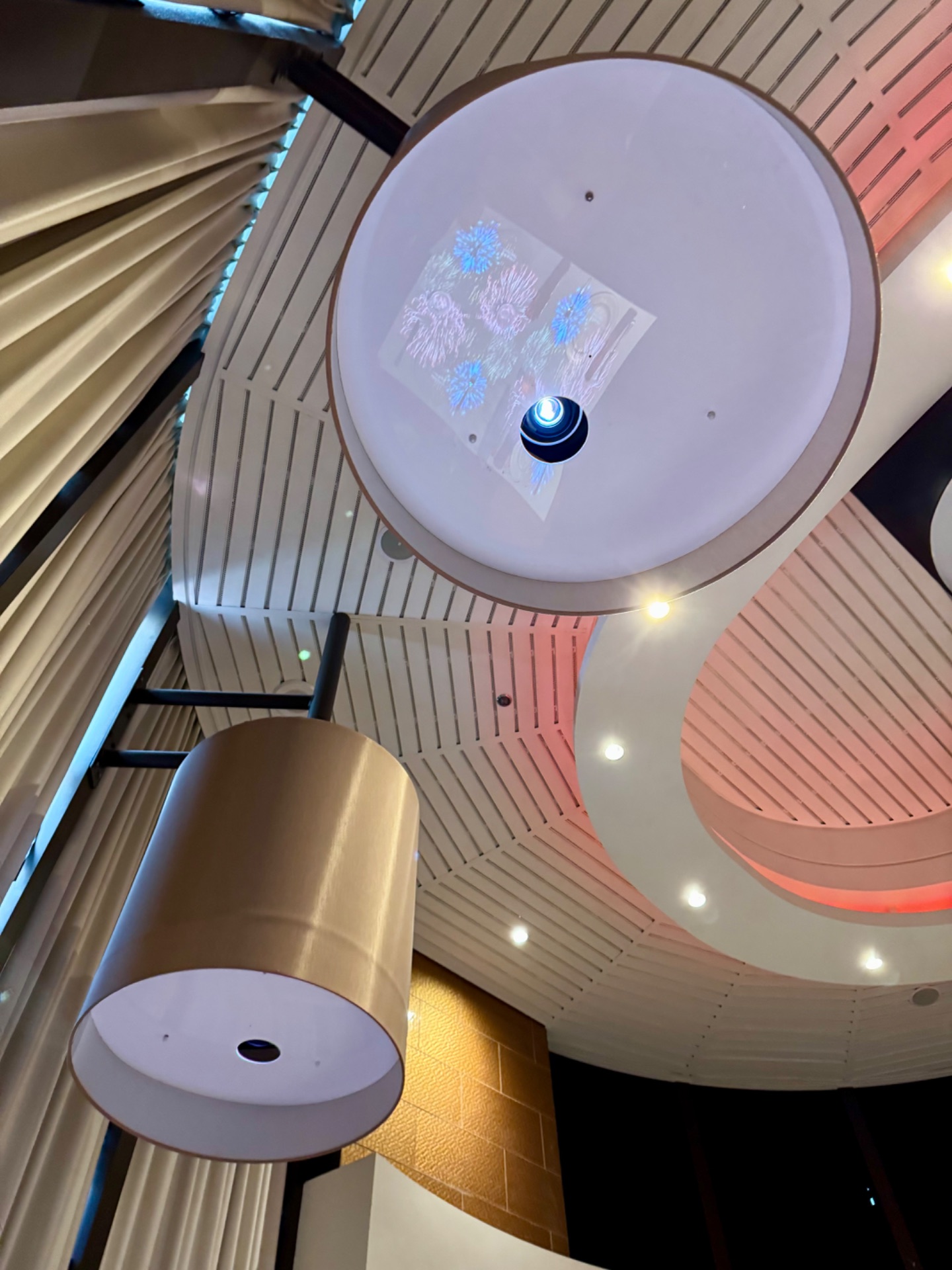 Modern cruise ship ceiling with interactive display showing blue snowflake patterns and a central sphere, surrounded by linear architectural design and ambient lighting.