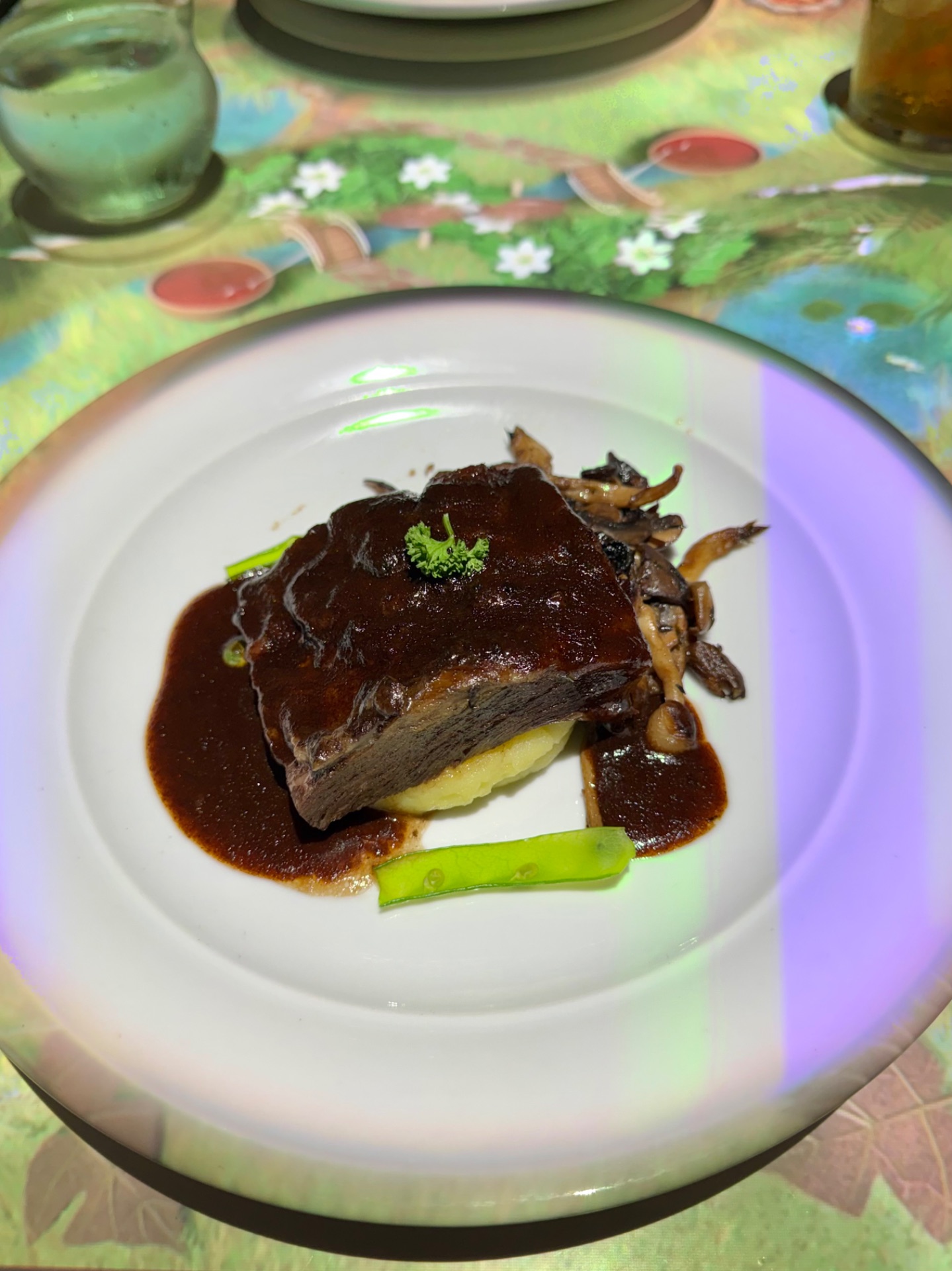Gourmet plated beef dish with red wine sauce, mushrooms, and green peas on white plate at fine dining restaurant.