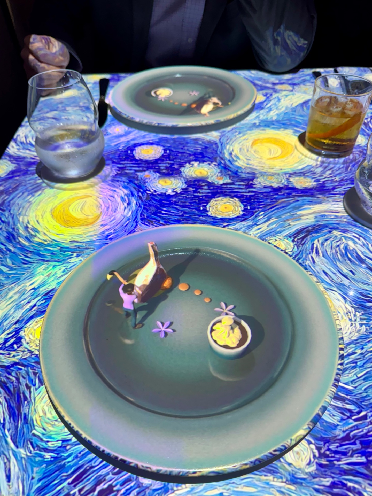 Immersive dining experience featuring interactive plates with animated characters against a starry night sky tablecloth design.