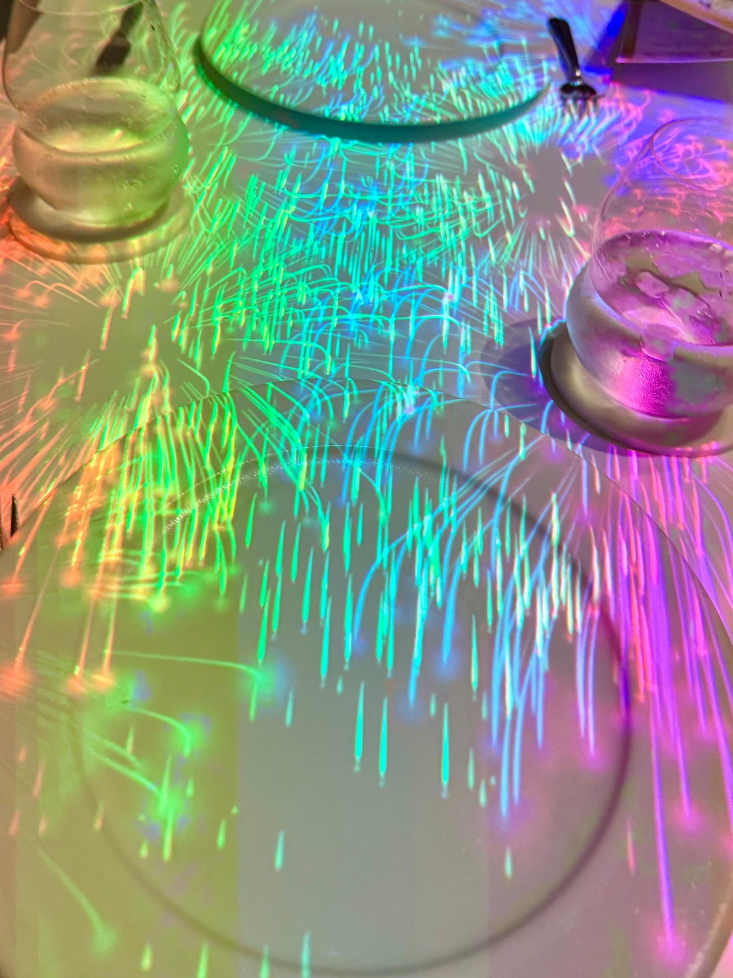 Colorful neon light projections on drinks and glasses at a cruise ship bar or lounge venue.