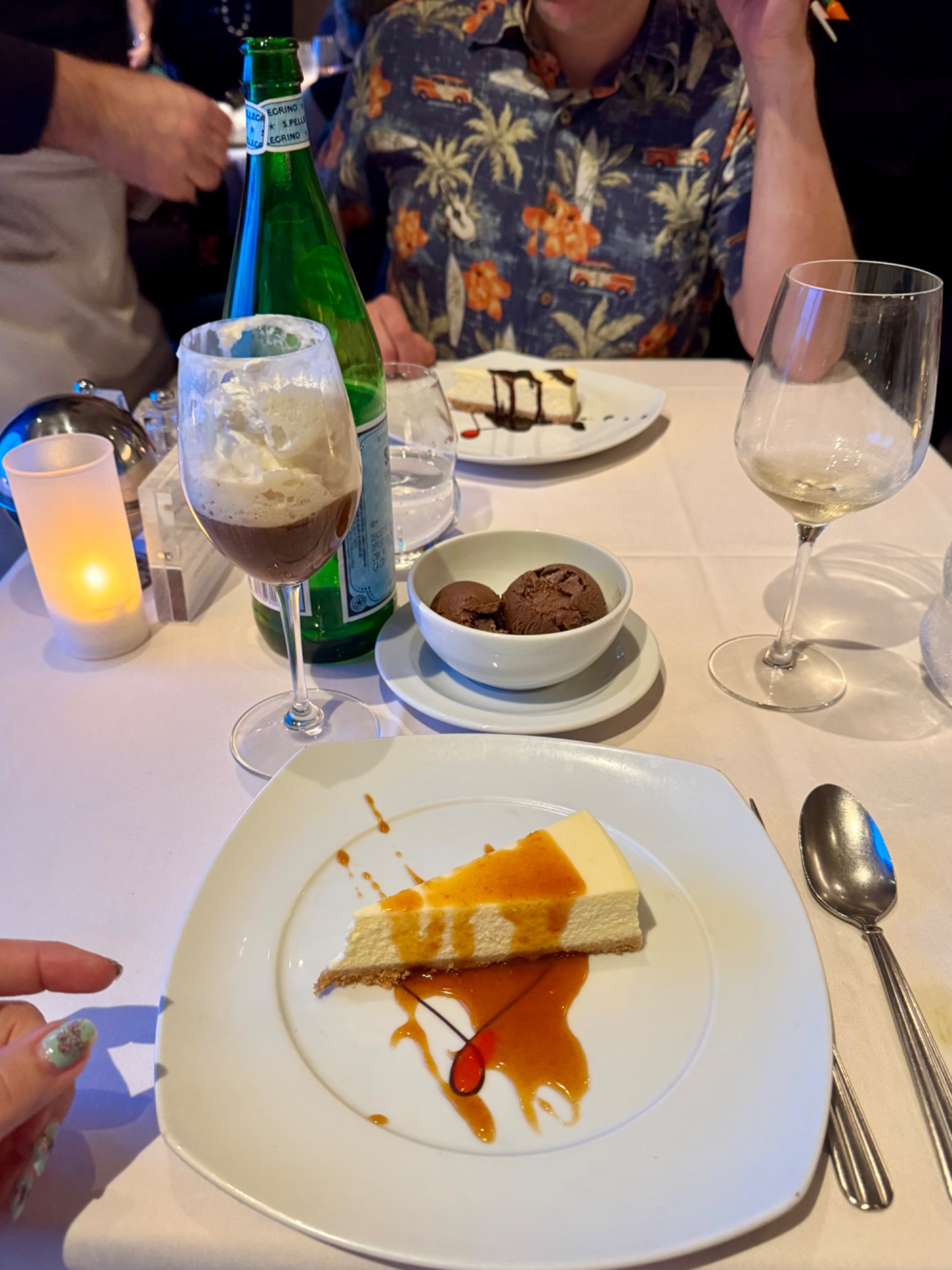 Fine dining dessert course on a cruise ship with cheesecake, chocolate ice cream, wine glasses, and elegant plating.