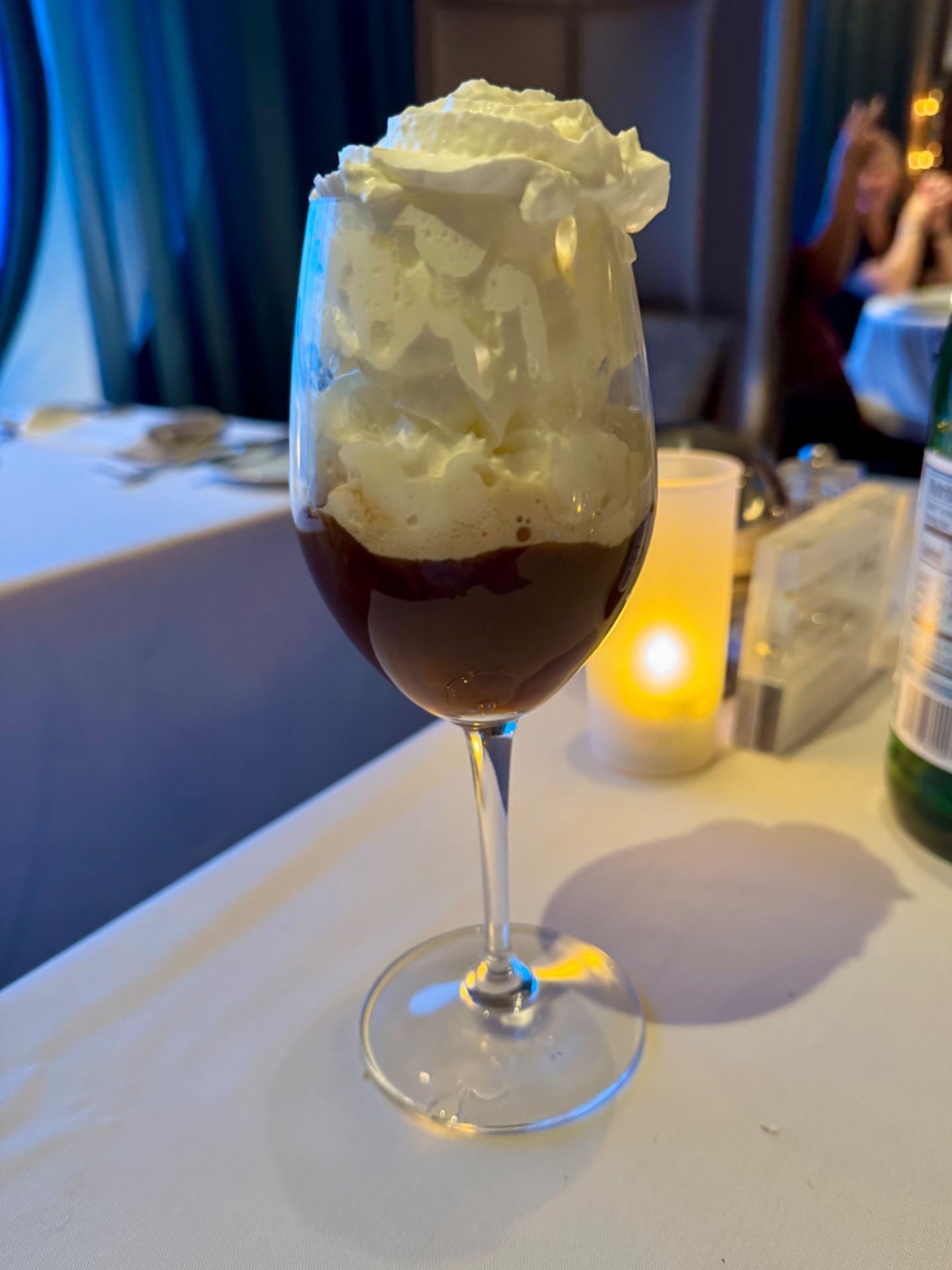 Elegant dessert drink with dark cola and vanilla ice cream topping served in a wine glass at a formal dinner event.