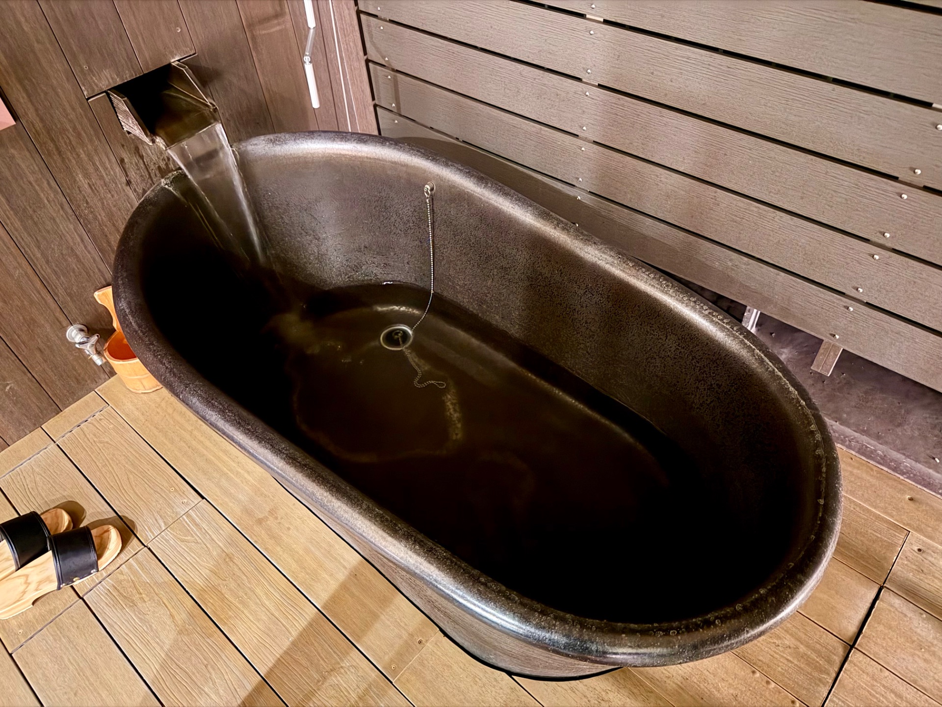 Japanese onsen bath filled with hot mineral water in a wooden spa room.