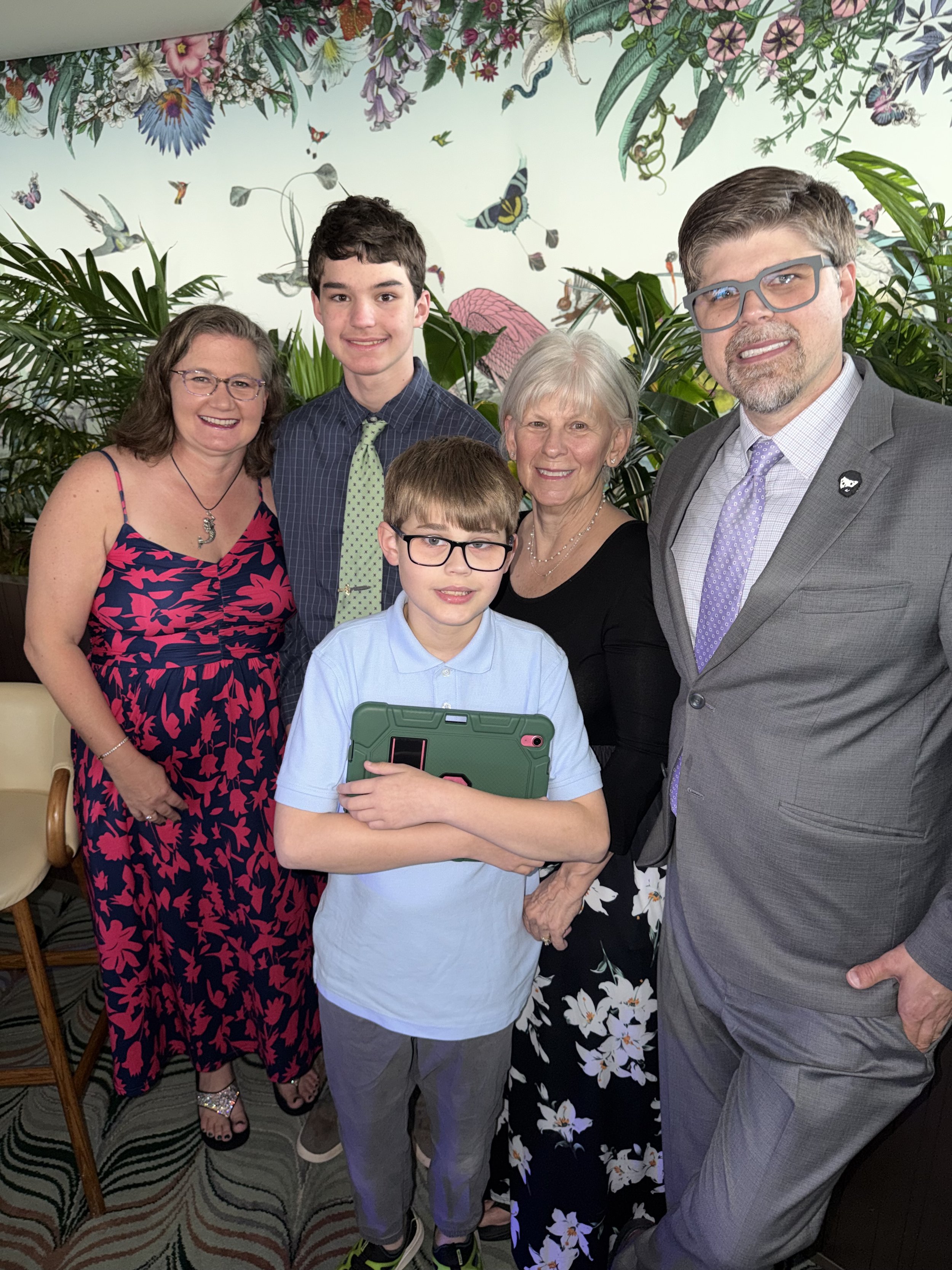 Family of five poses together in botanical garden room