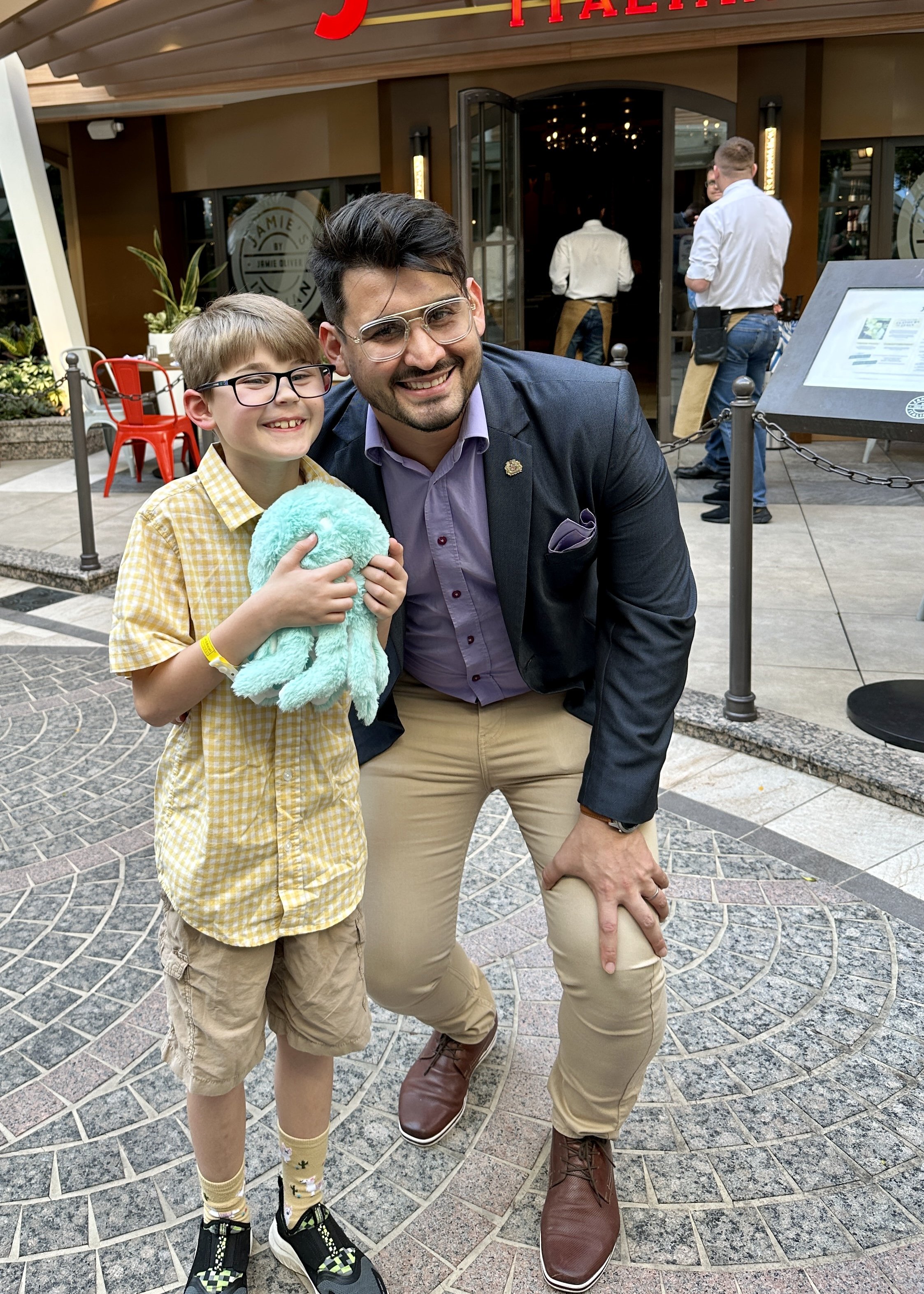 Adult man and child posing with stuffed animal at mall