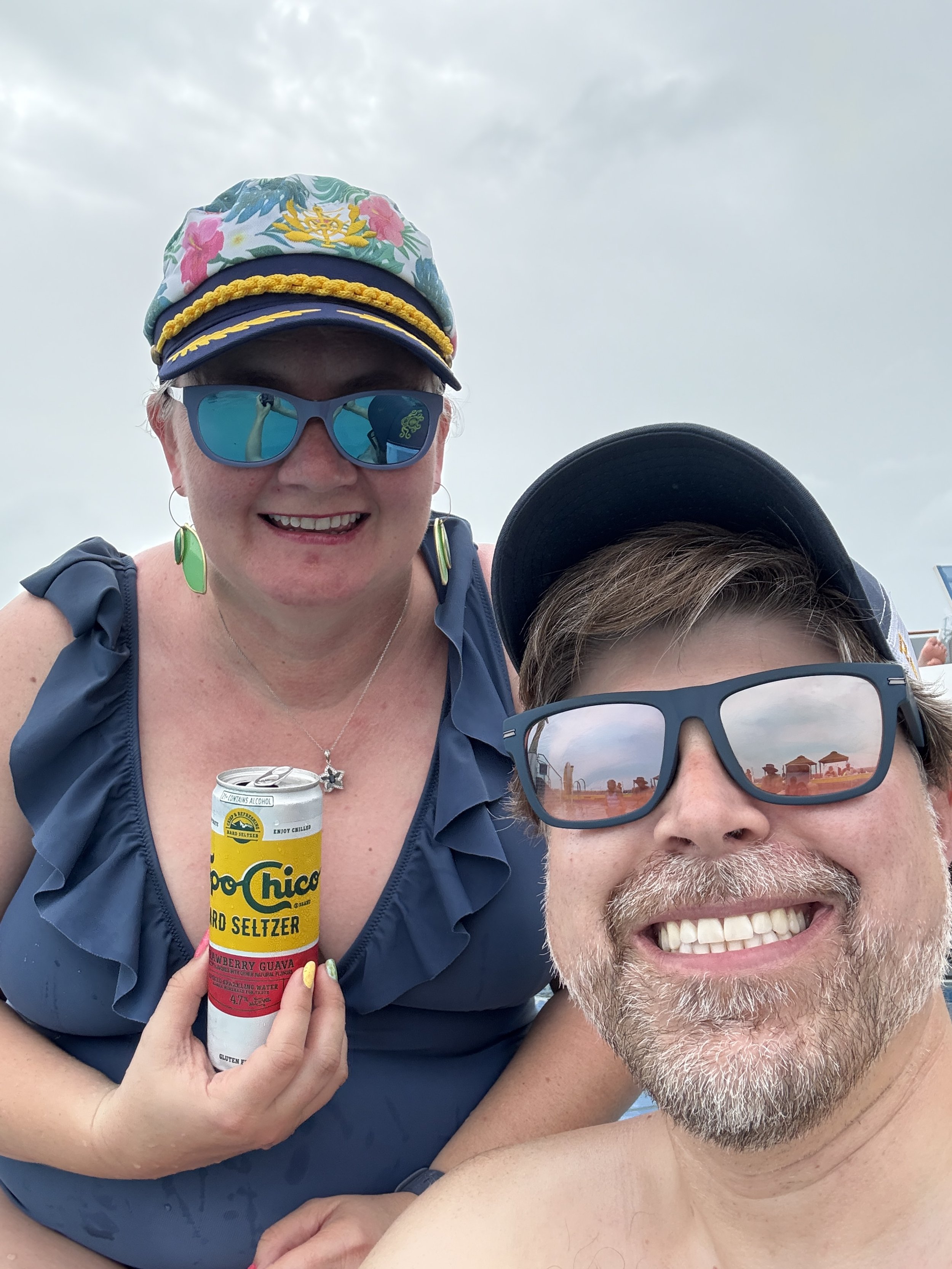 Two people enjoying Topo Chico hard seltzer on cruise ship deck
