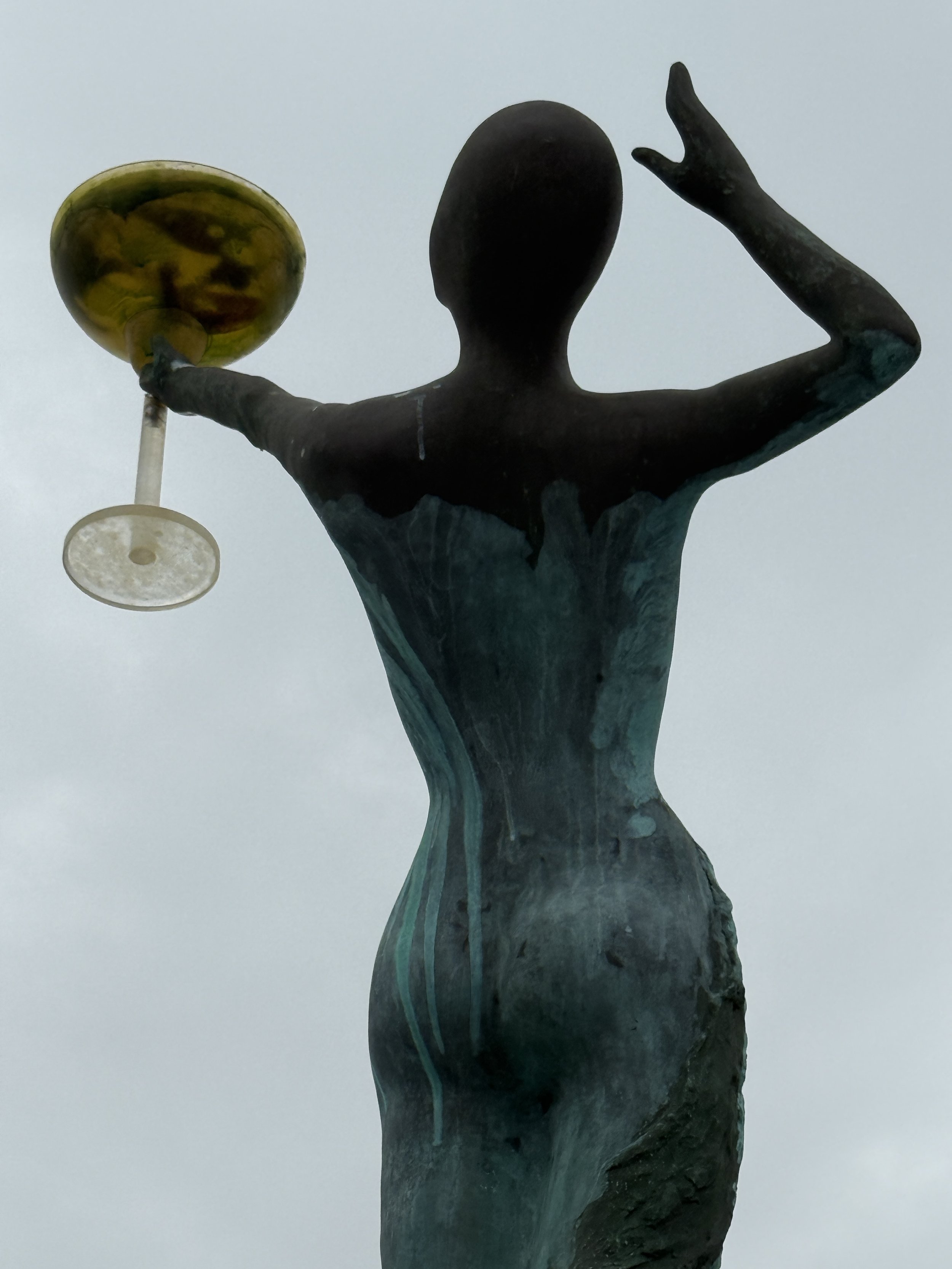Bronze statue holding golden bowl, patina weathered green
