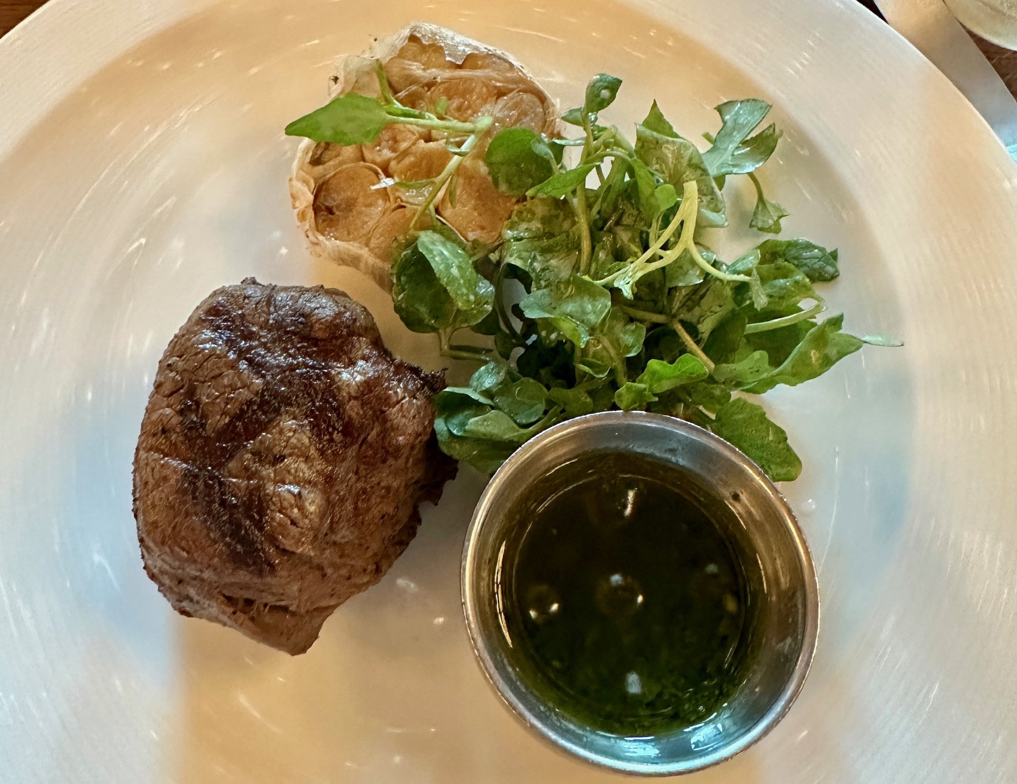 Gourmet steak dinner with microgreens and herb oil sauce