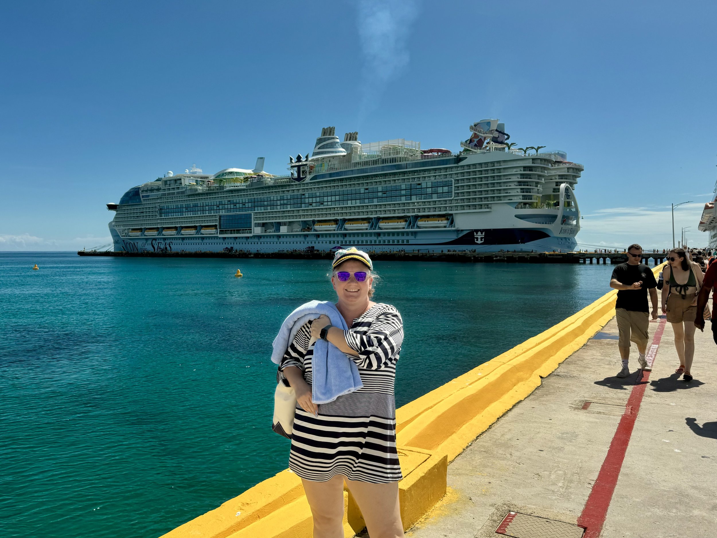 Woman poses at dock with Symphony of the Seas cruise ship