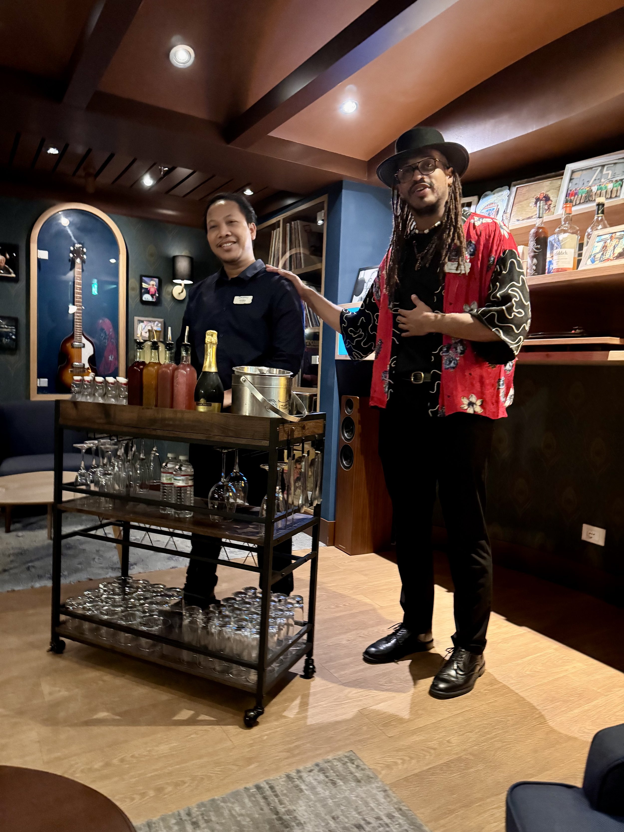 Man in red jacket presenting beverages at ship bar counter