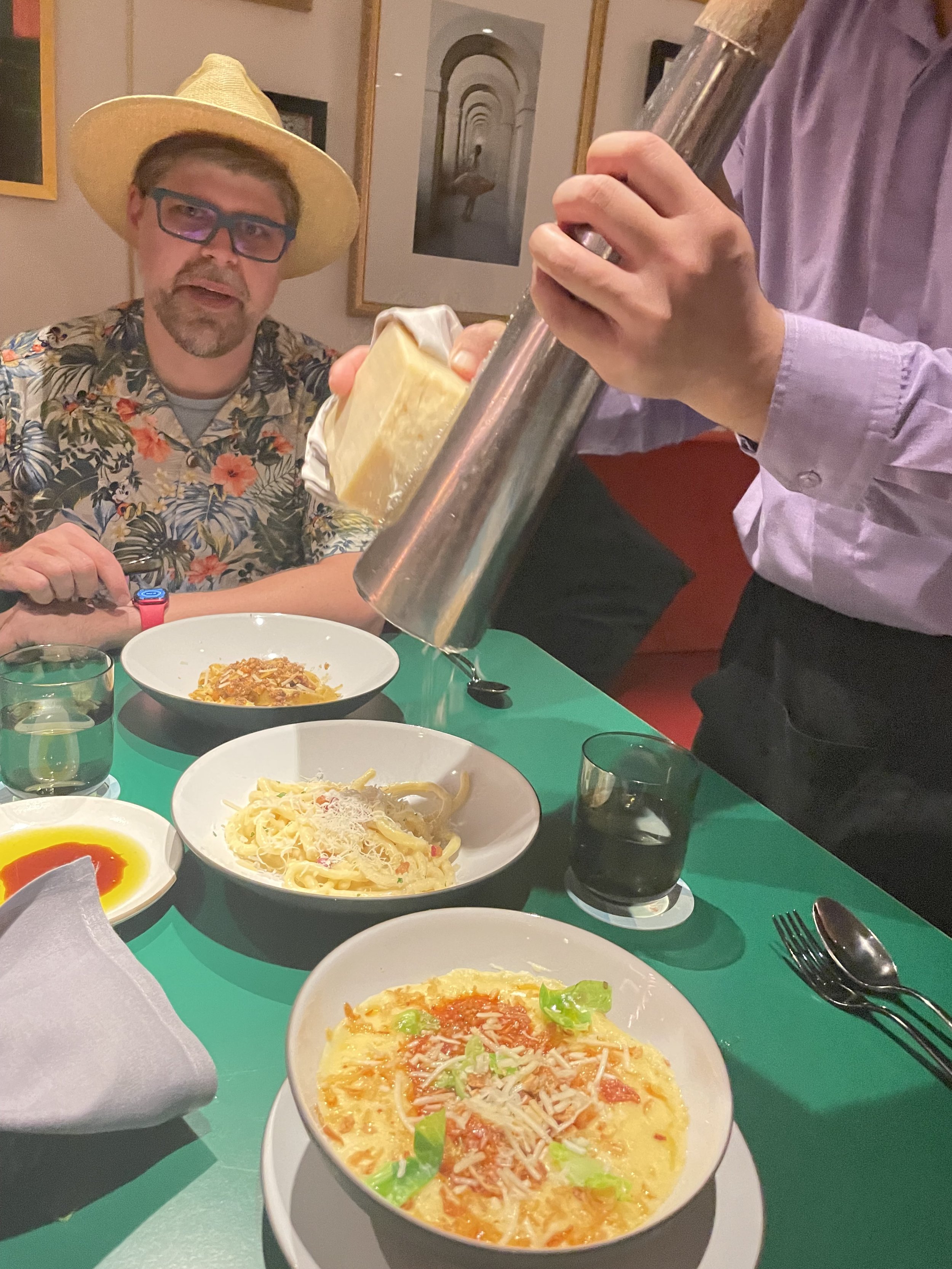 Man in cowboy hat dining on pasta at restaurant table