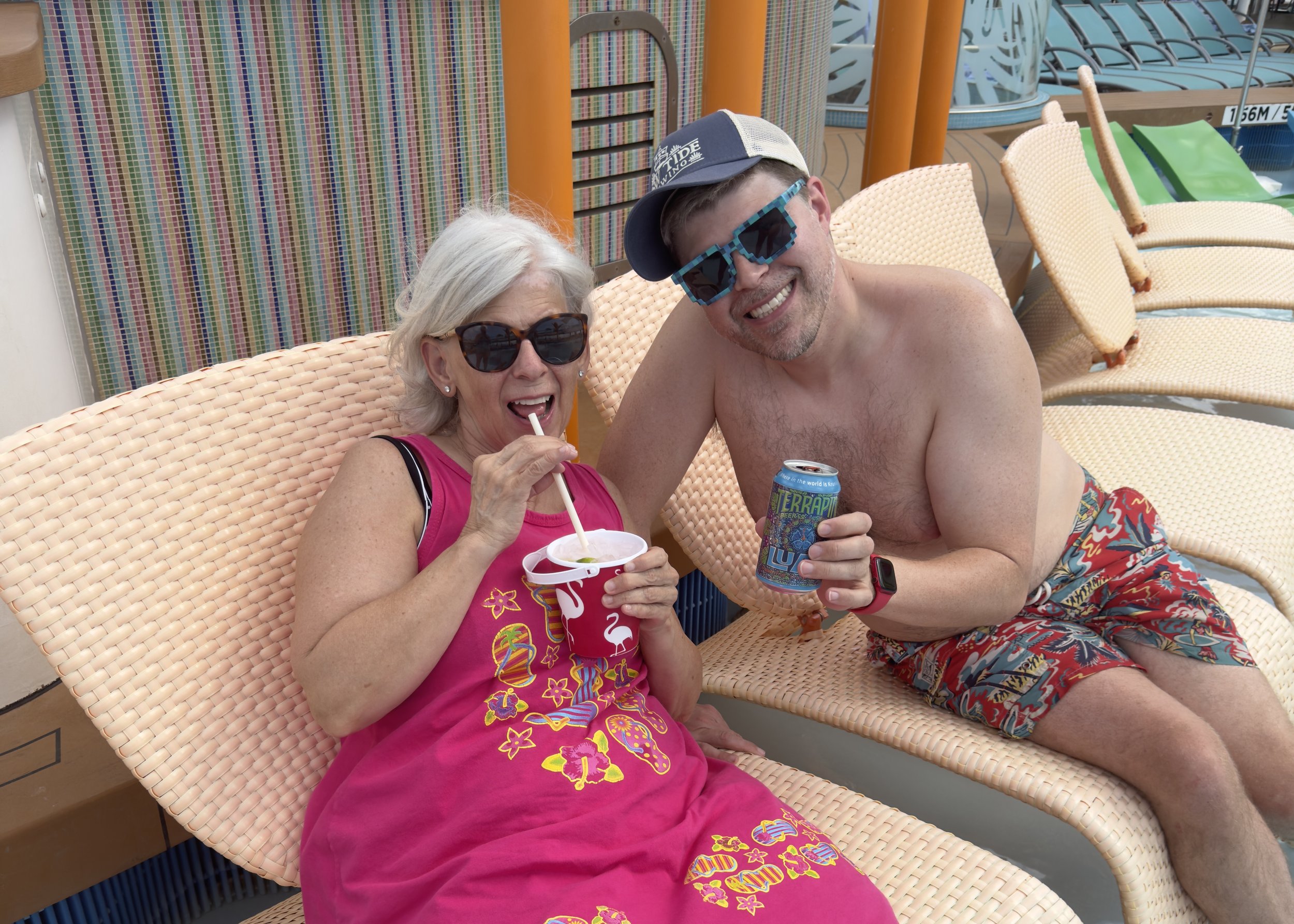 # Couple enjoying drinks and laughter on cruise ship deck chairs
