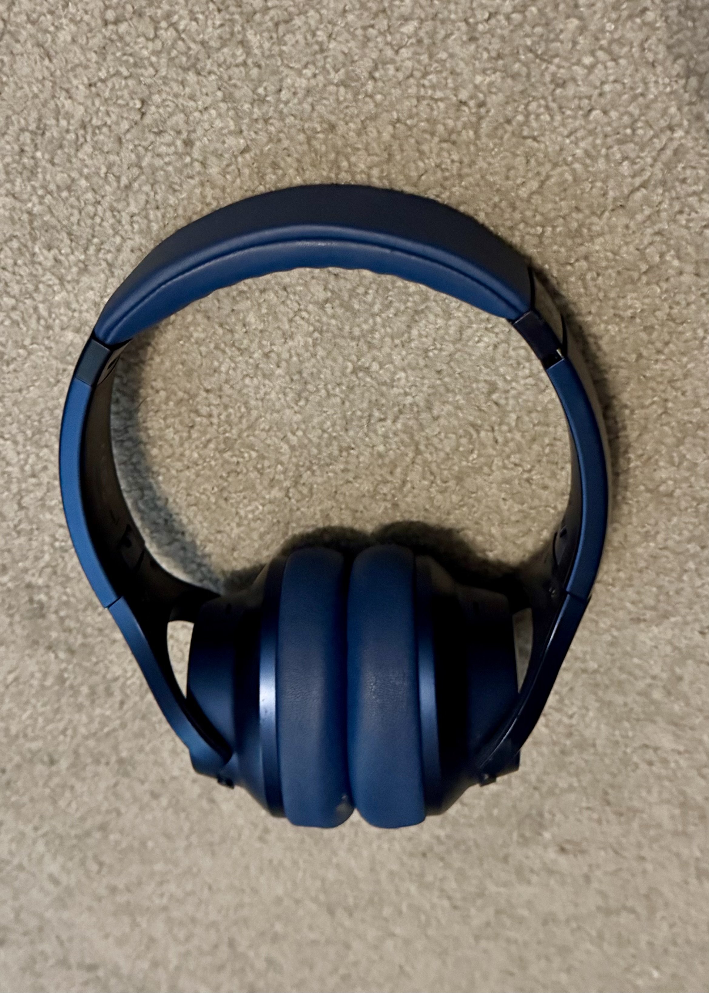 Blue over-ear headphones on textured beige surface